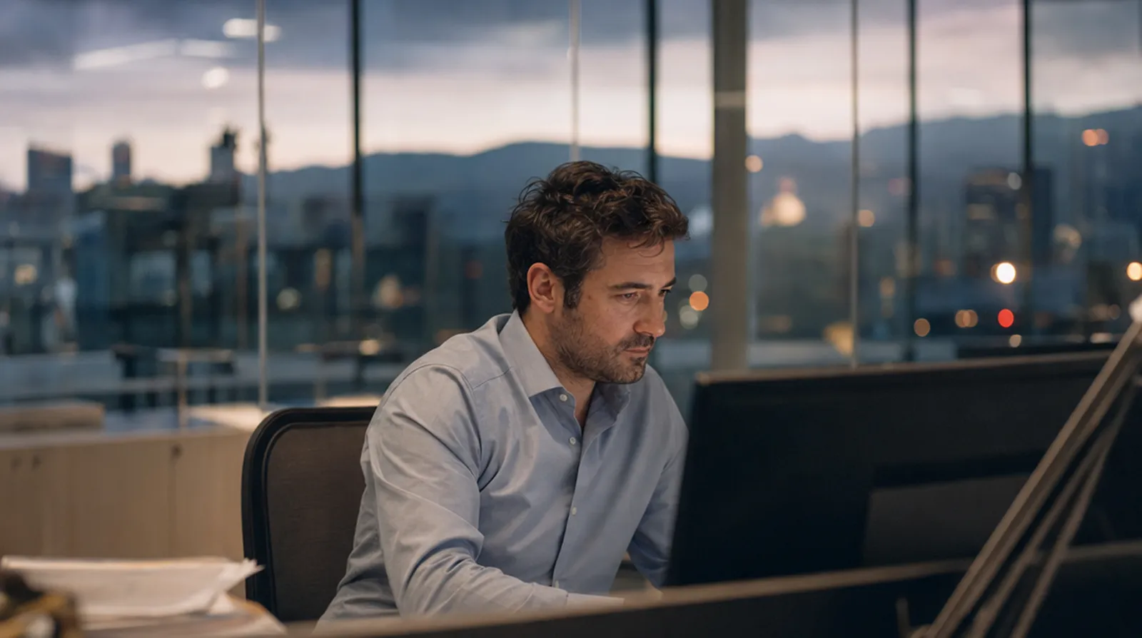 Analista financiero repasando cifras al anochecer en una oficina de Barcelona